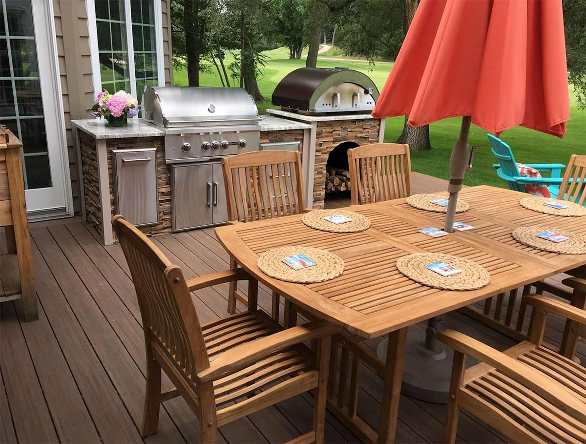 linear outdoor outdoor kitchen with pizza oven on deck with kitchen table umbrella and chairs