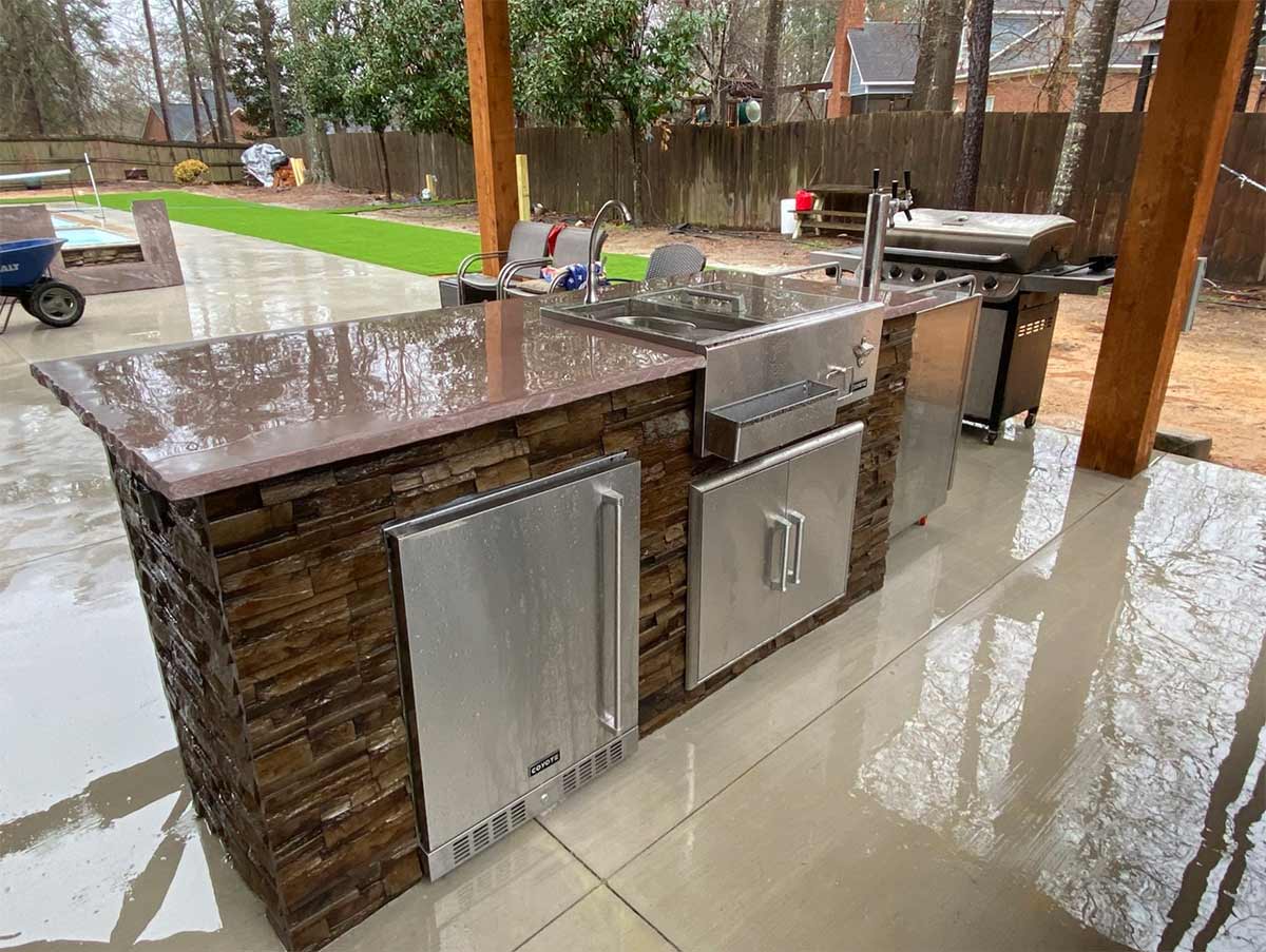 Types of refrigerators showing a linear refreshment and refrigerator island with kegerator next to it on patio