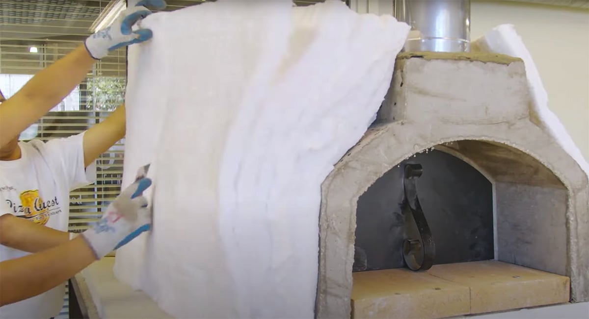 man applying insulation on pizza oven