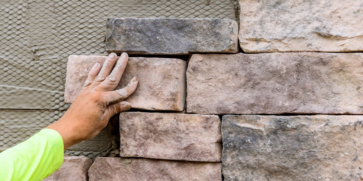 man applying stone to an outdoor kitchen