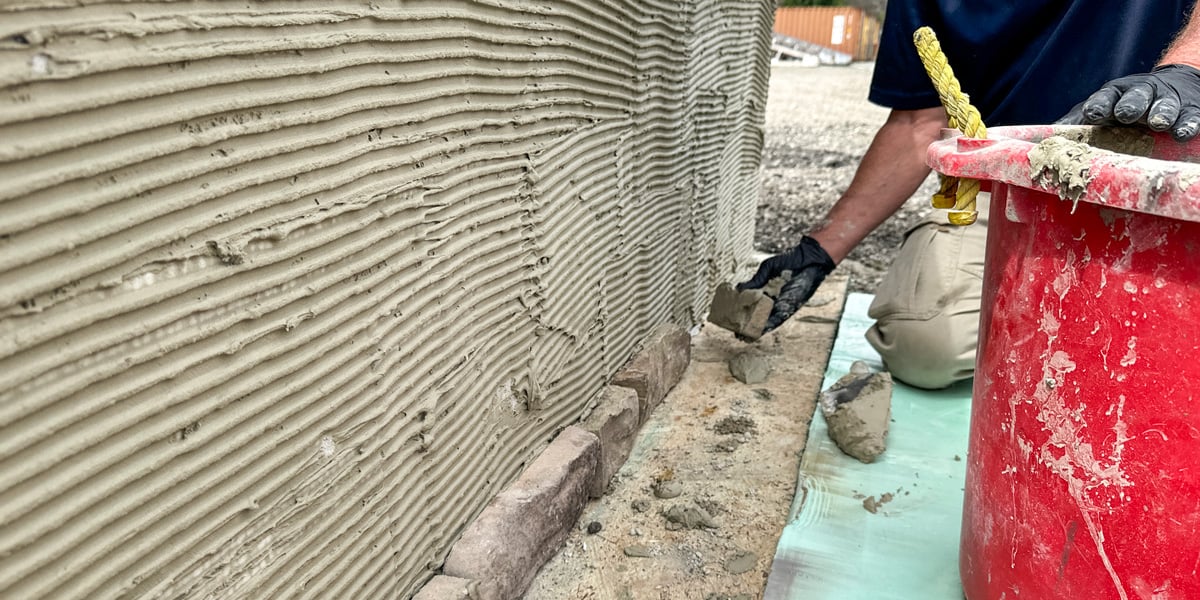 man applying stone veneer finish to outdoor kitchen