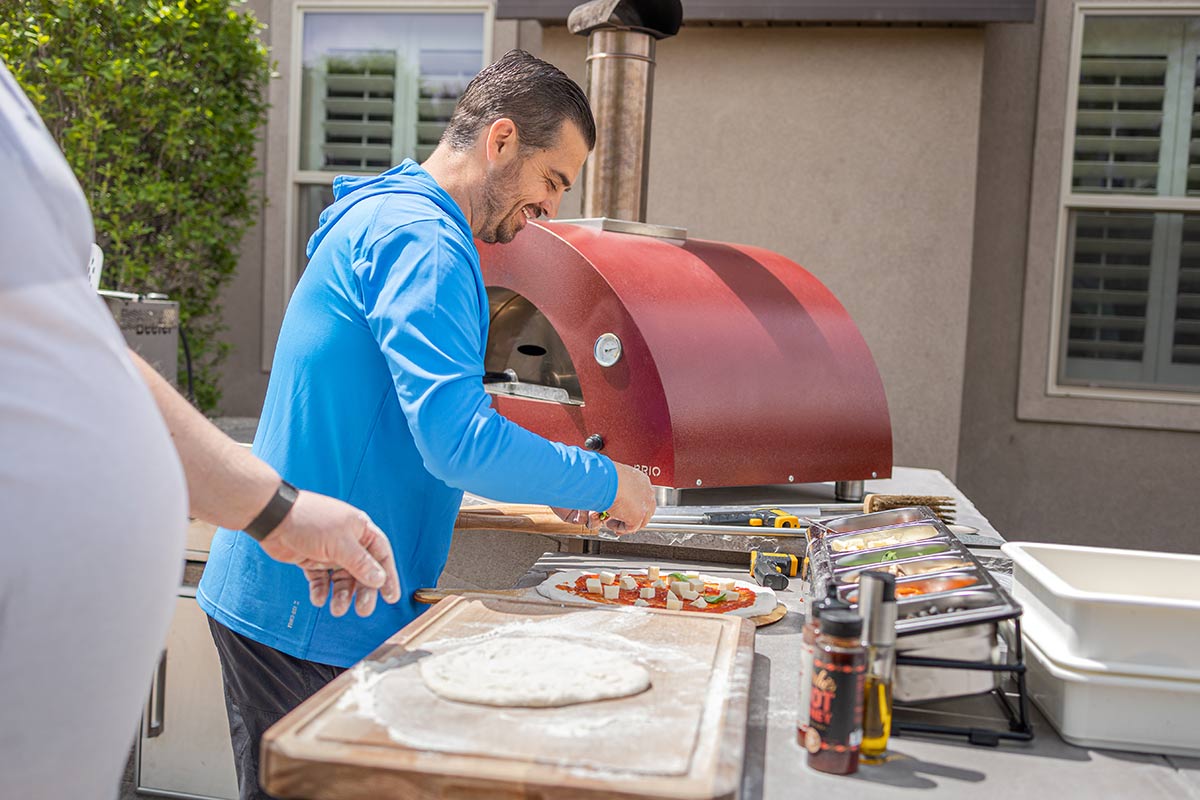 man assembling pizza by gas pizza oven