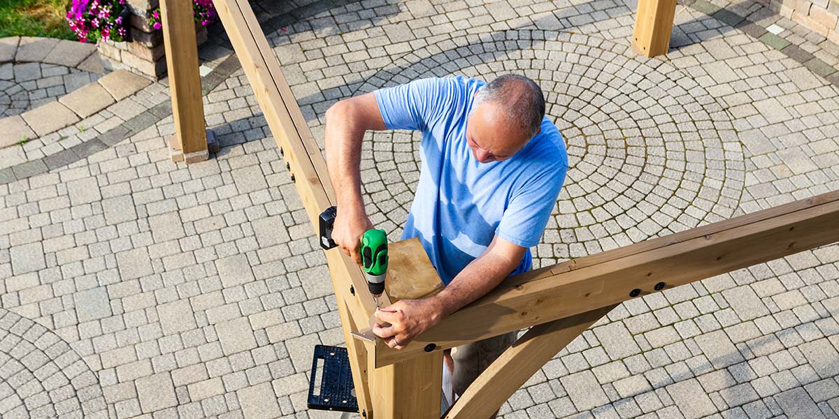 man building a diy outdoor kitchen roof structure out of wood