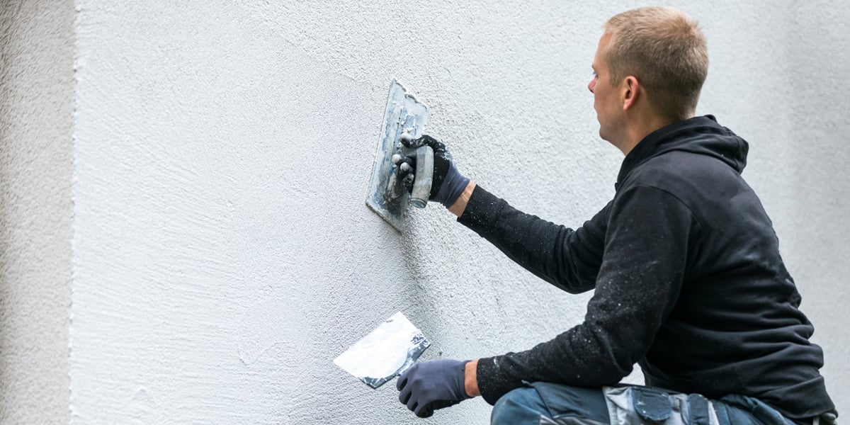 man cladding stucco to a wall