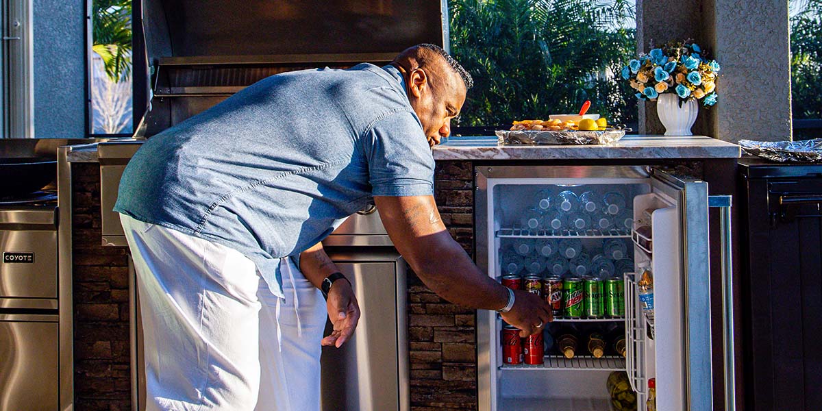 man getting a drink out of his outdoor fridge in an rta outdoor kitchen
