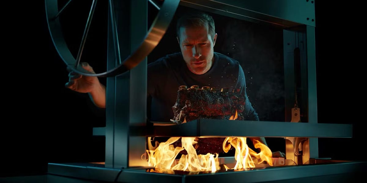 man grilling beef on argentinian grill