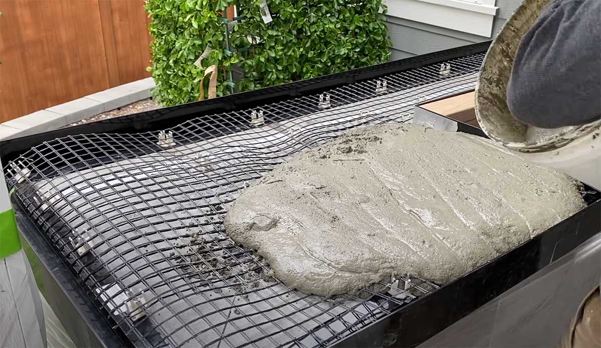 man pouring concrete into concrete countertop form