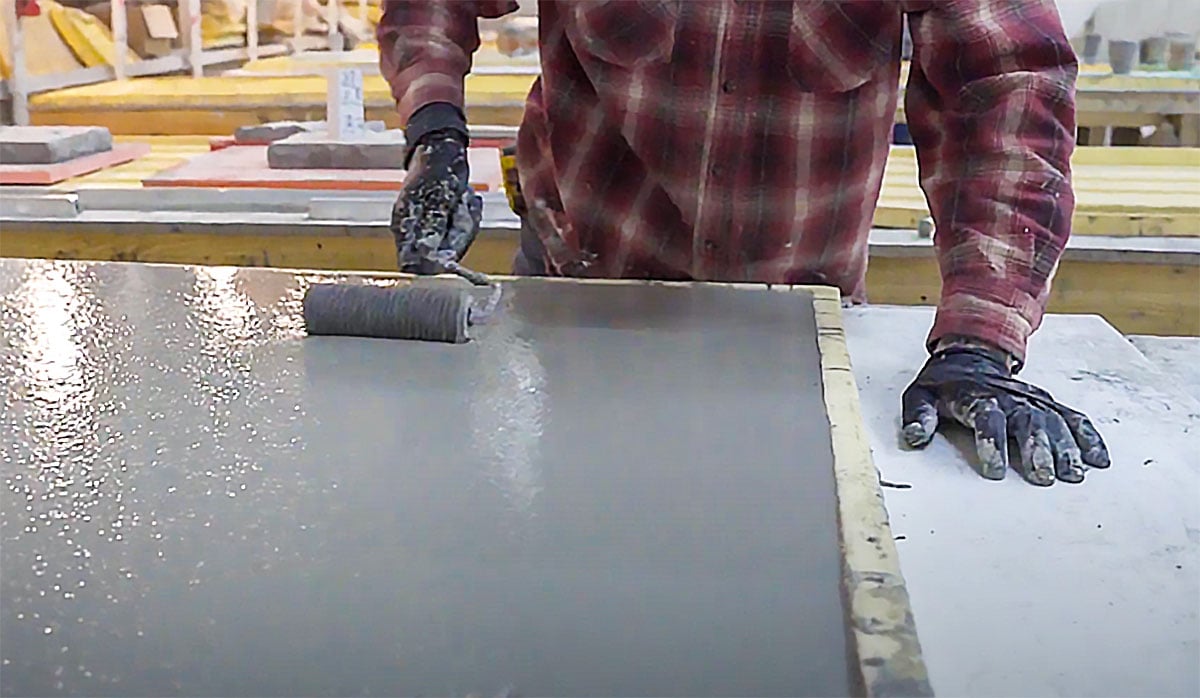 man smoothing out concrete with paint roller in countertop mold