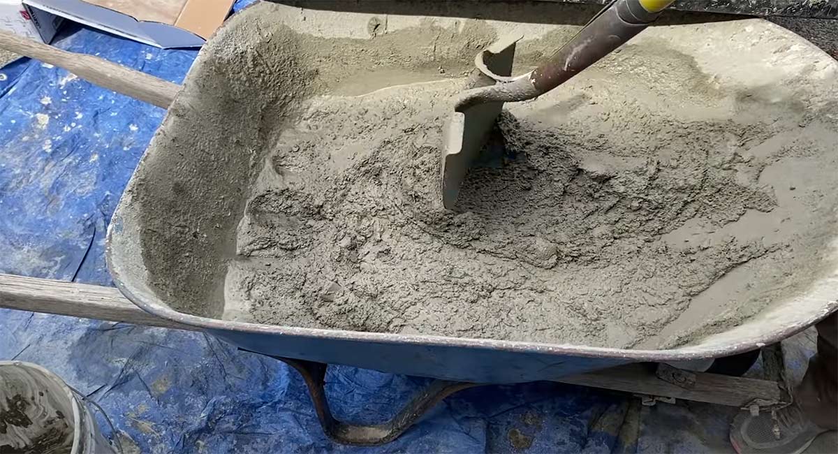man stirring a wheelbarrow full of concrete mix for use on diy concrete countertop