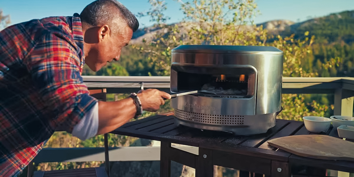 man turning pizza in solo stove portable oven