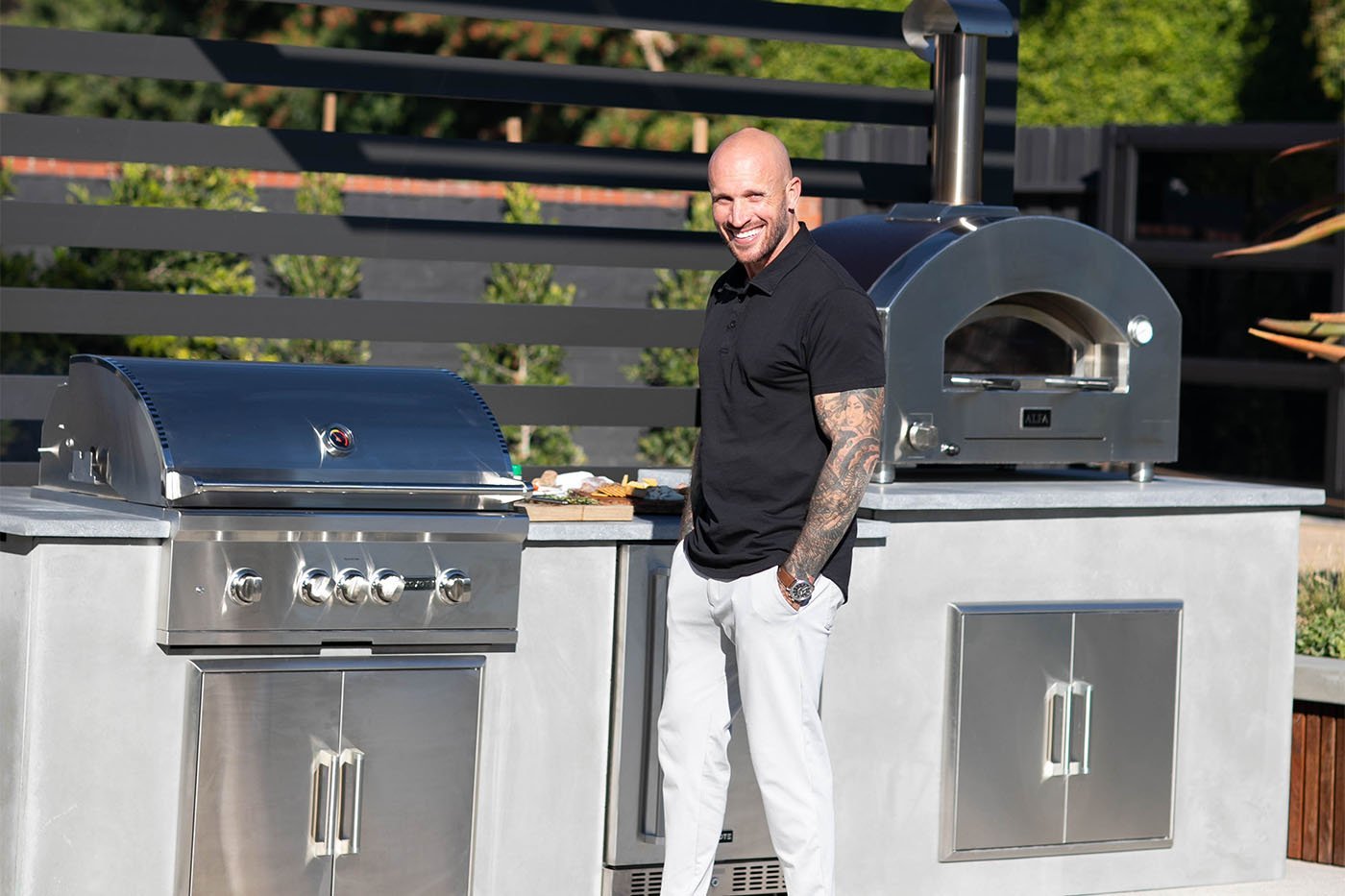 mike pyle in front of his modern outdoor kitchen with pizza oven