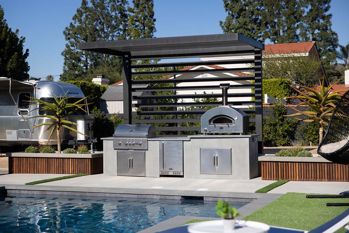 modern concrete summer kitchen with pergola and landscaped area