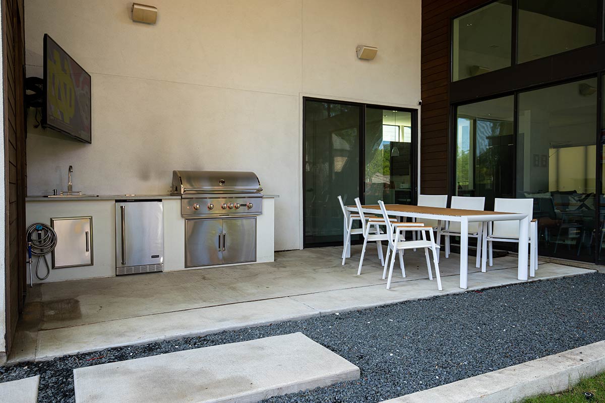 outdoor grill island on patio next to house with table and seating