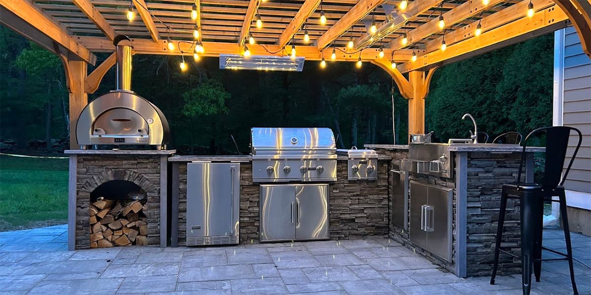 covered outdoor kitchen and bar under pergola with pizza oven