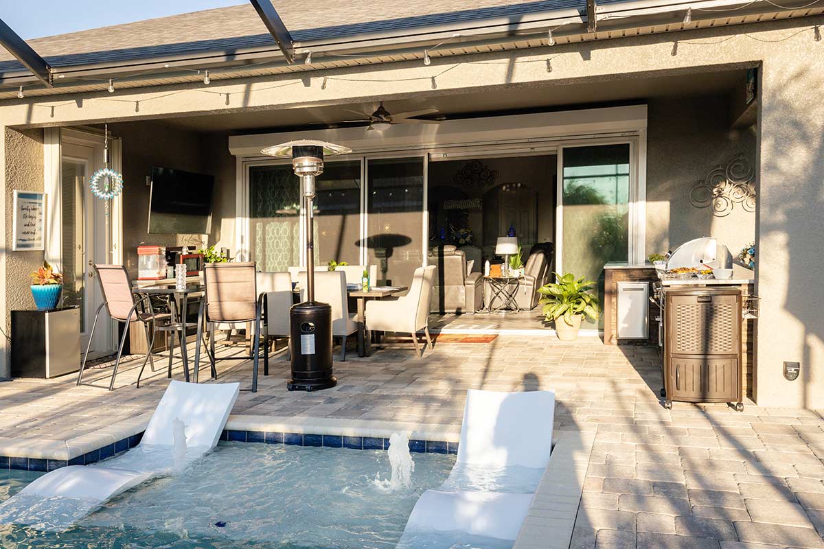 outdoor kitchen and living space by pool on patio