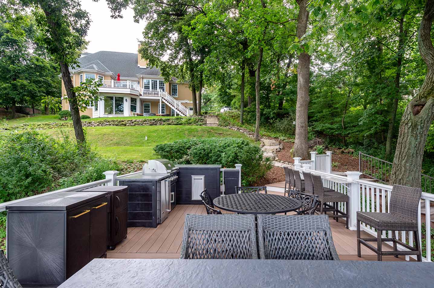 outdoor kitchen on deck with wrought iron style dining table and chairs