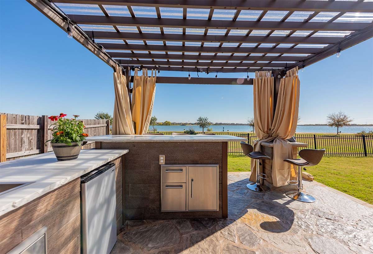 outdoor kitchen with bar seating on patio under a pergola