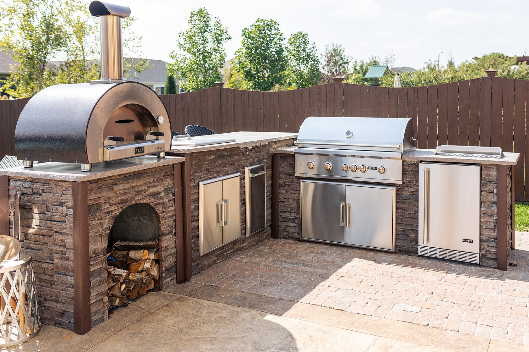 outdoor kitchen with wood fired pizza oven and fridge