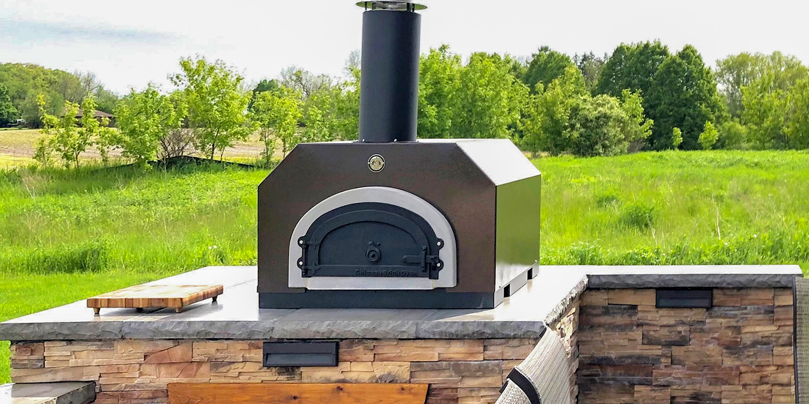 outdoor pizza oven in backyard on stone stand