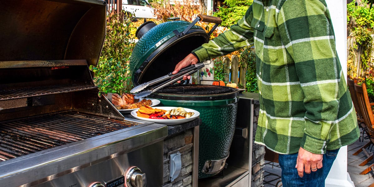 person grilling food with gas grill and kamado grill