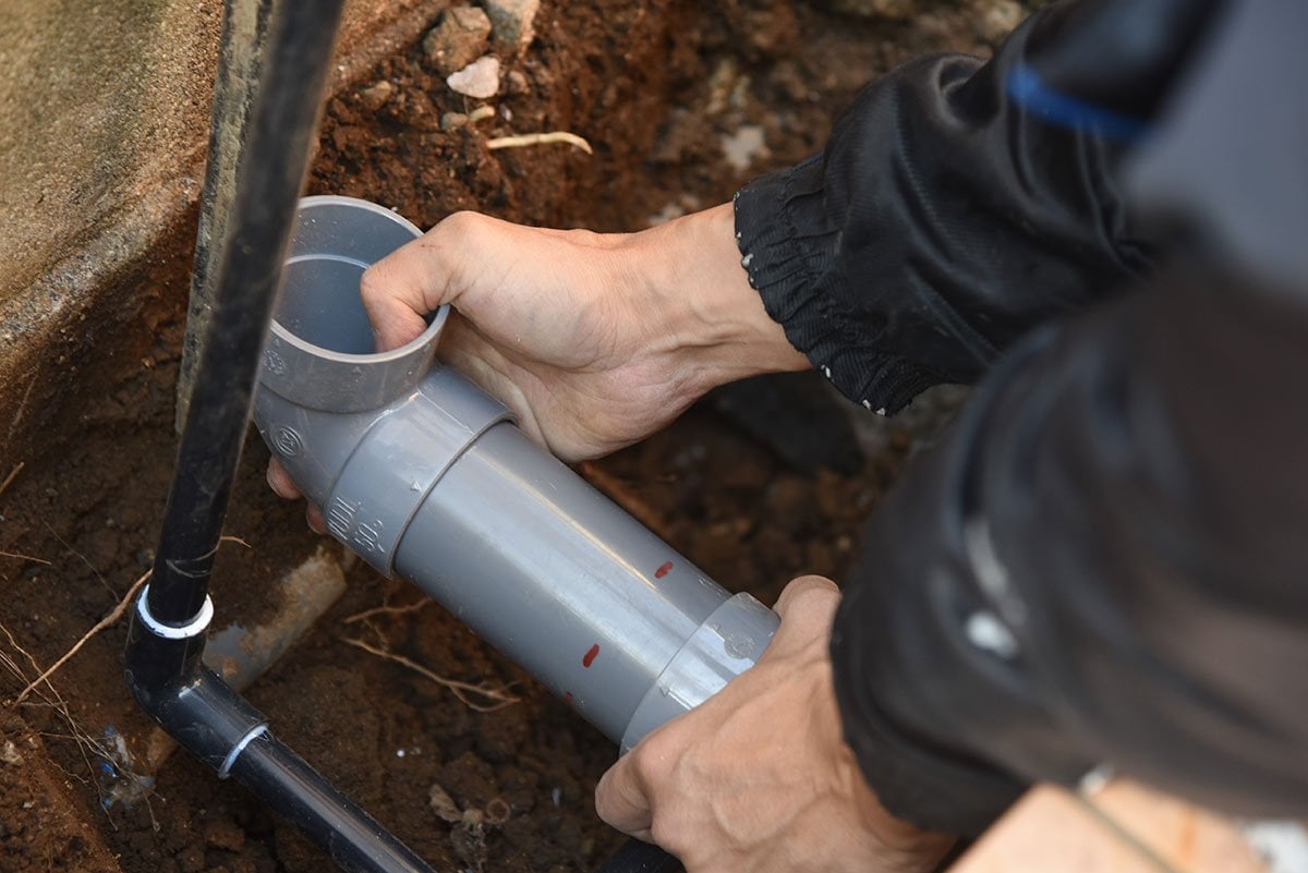 person installing drain pipe for an outdoor kitchen sink