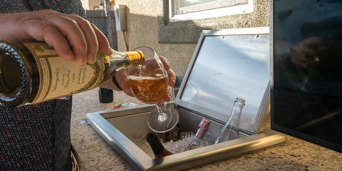 person pouring wine by drop in cooler