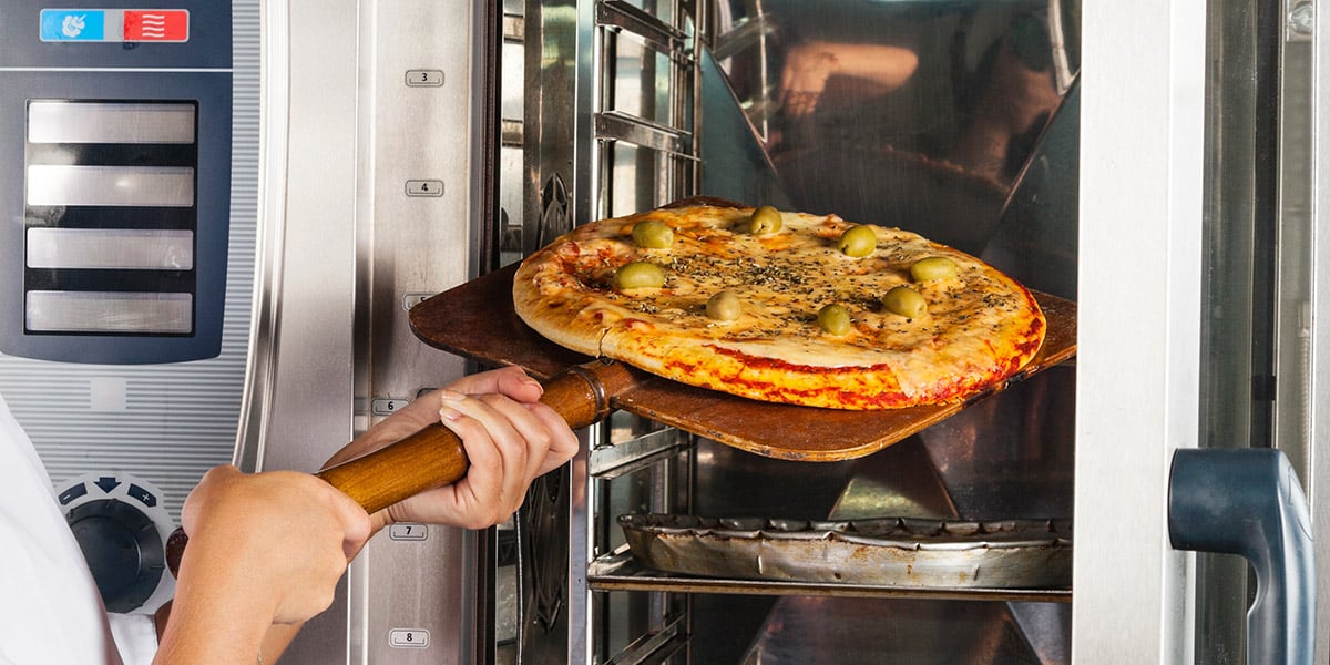 Pizza being put into convection oven