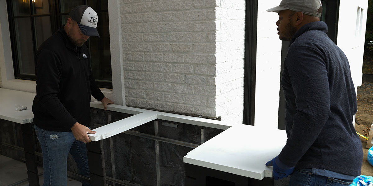pro installer setting countertop on outdoor kitchen structure