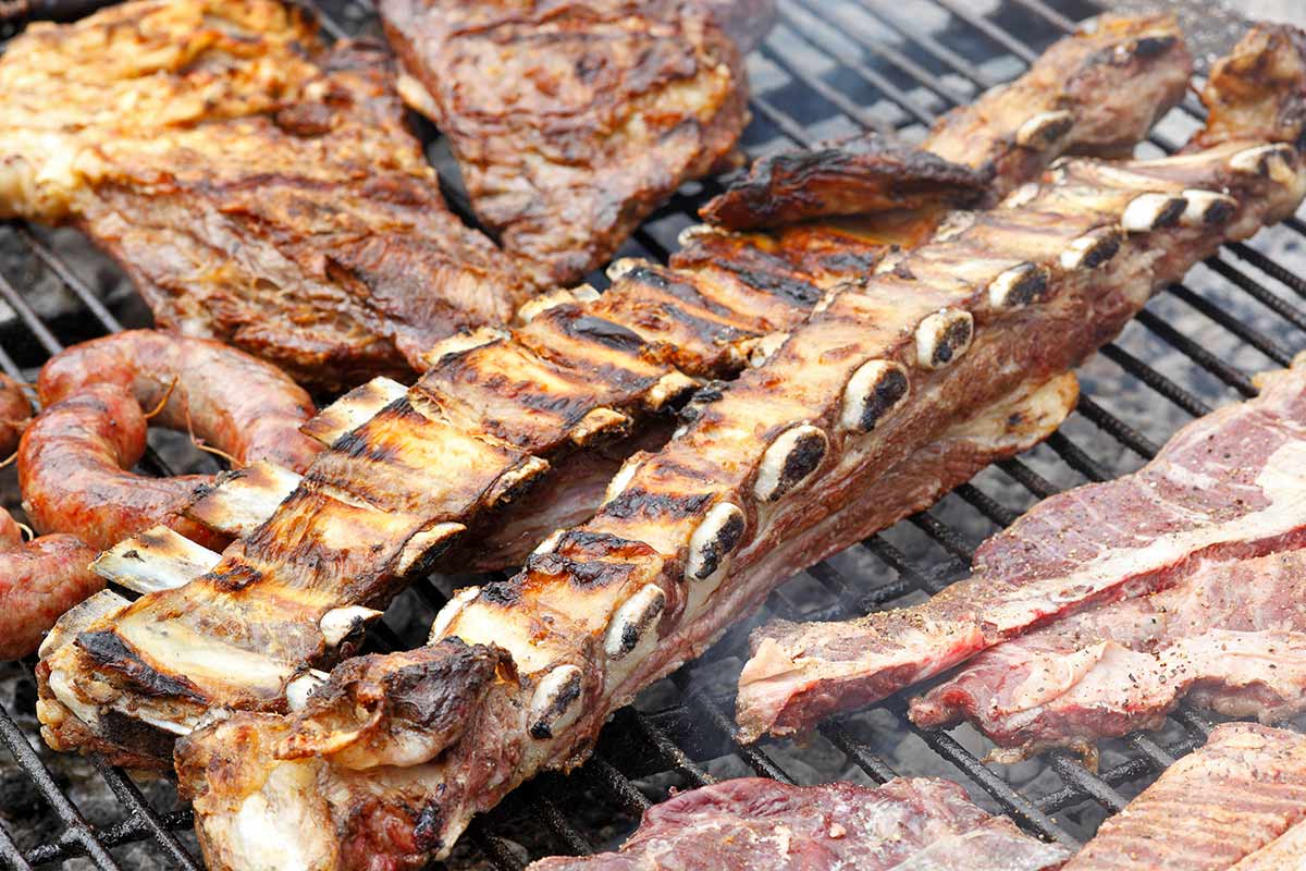ribs and other meats being grilled on Argentinian grill