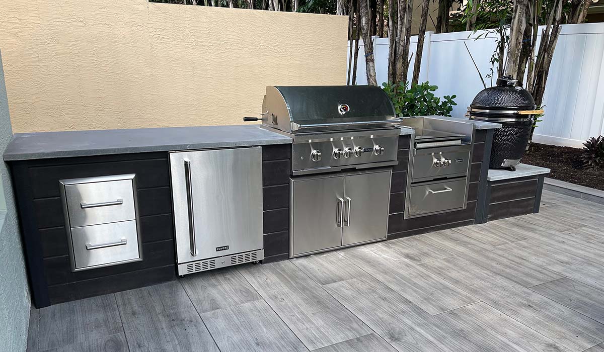 rta outdoor kitchen with dark plank finish and coyote appliances including a power burner and asado