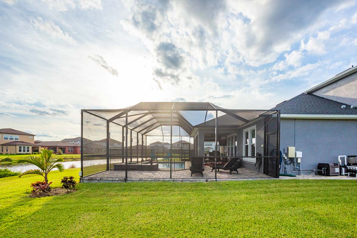 shot of a florida room from the outside that has an outdoor kitchen and pool inside it