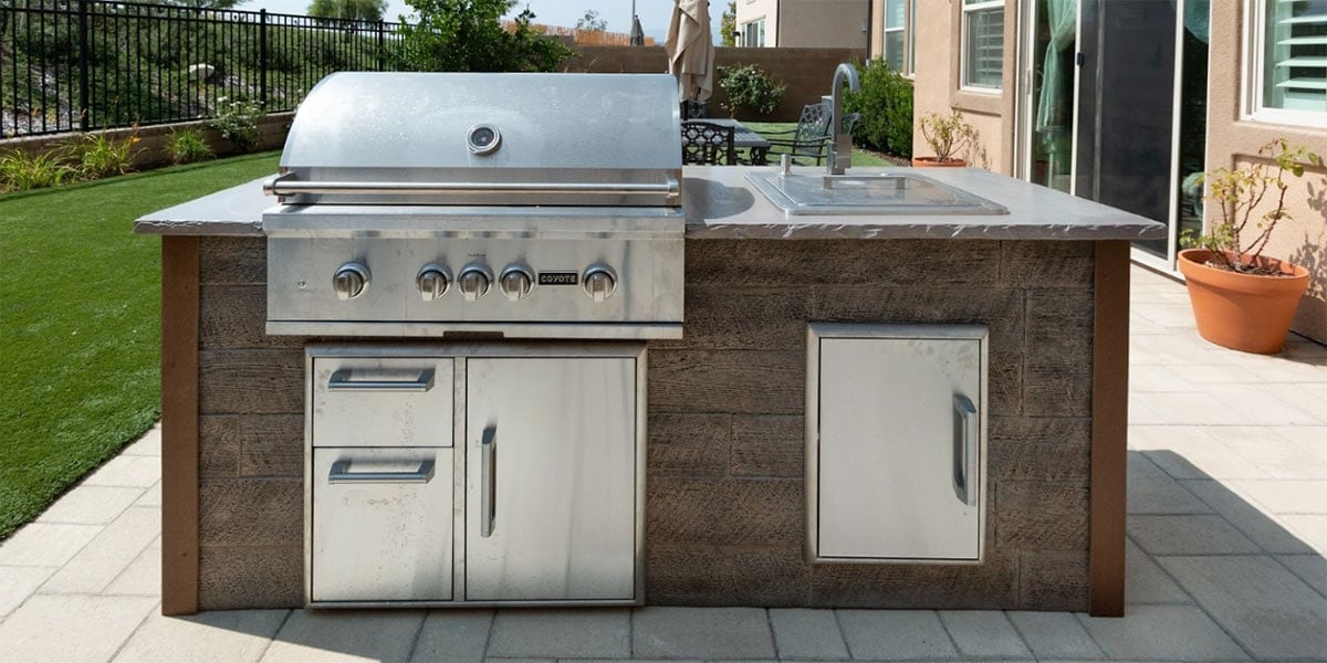 simple outdoor kitchen with gas grill and sink in a backyard