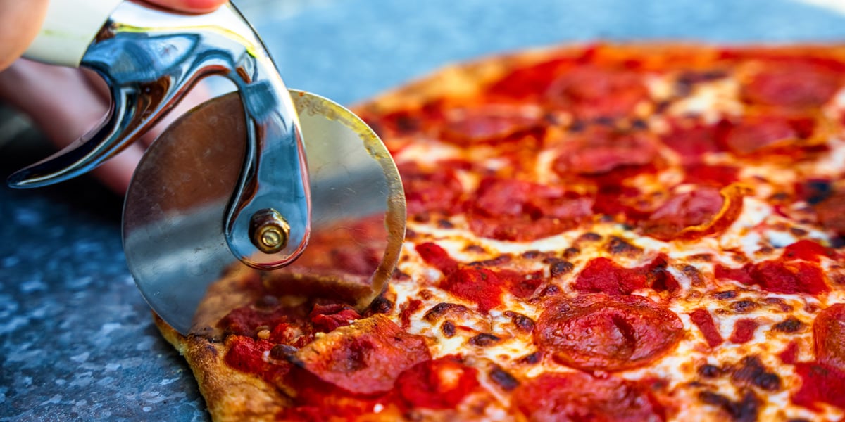 slicing a thin crust pepperoni pizza