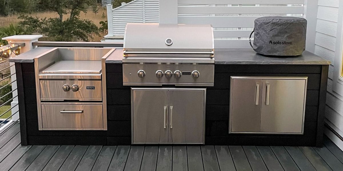 small outdoor grill area on deck next to house with power burner and dry pantry storage