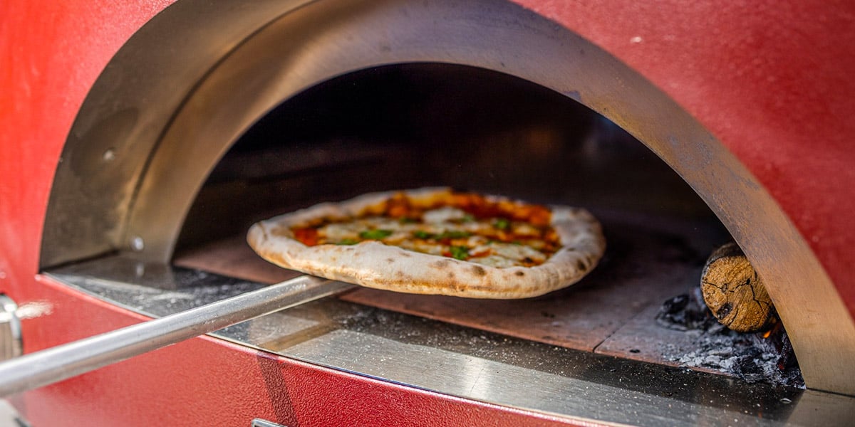 small pizza being launched into alfa pizza oven