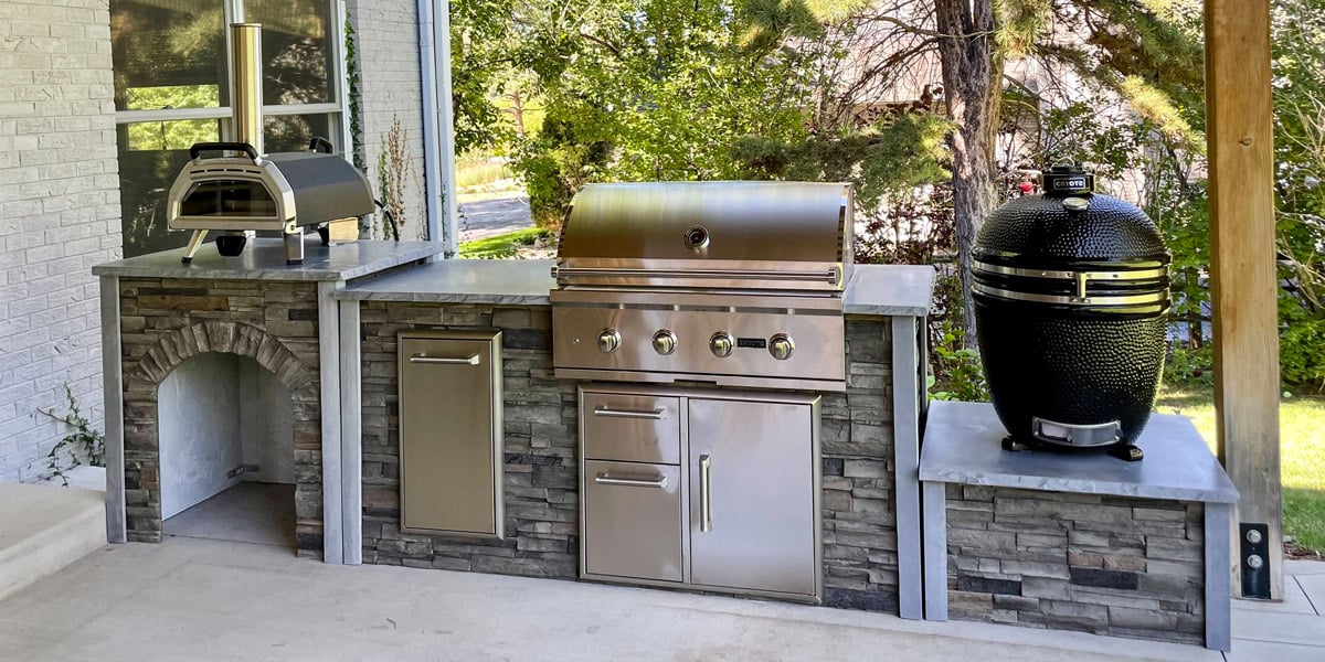 stacked stone graphite small backyard bbq area design with gas grill, dual storage / access and pull out trash