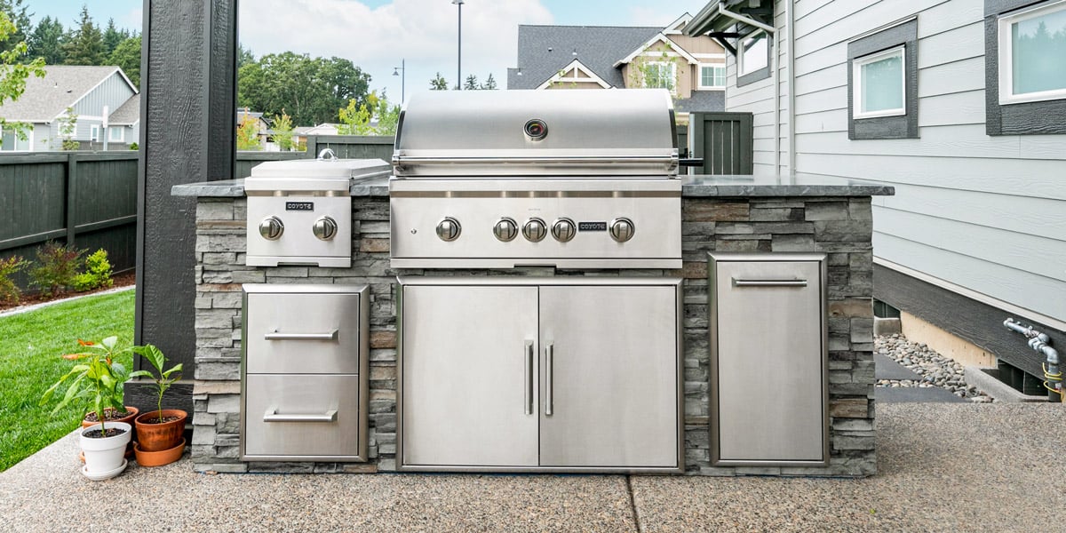 stacked stone simple outdoor kitchen on paver patio with side burner trash and storage drawers