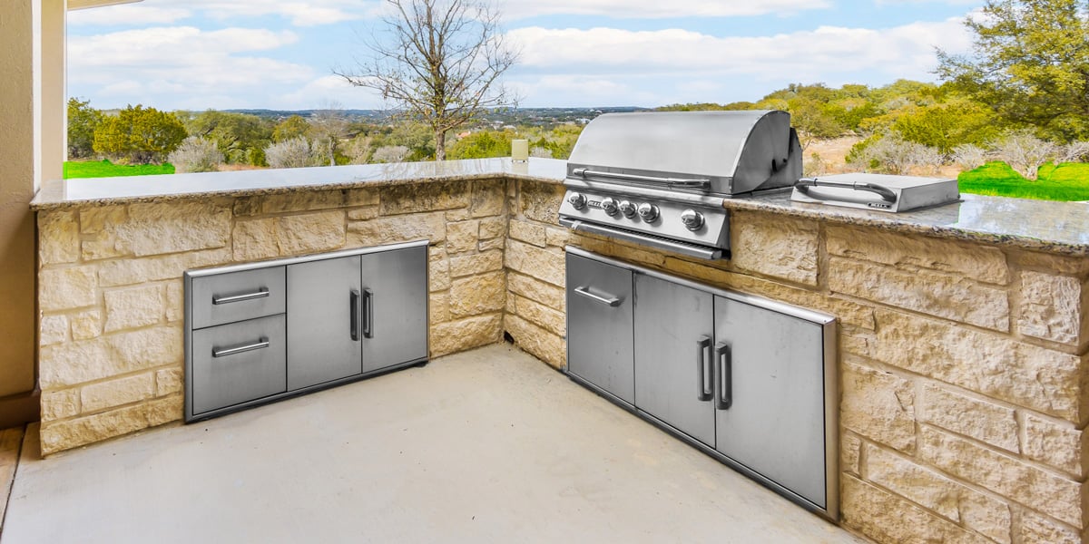 stone outdoor kitchen on concrete patio
