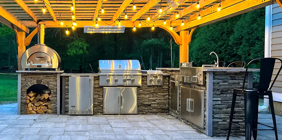 stone outdoor kitchen with pizza oven on paver patio
