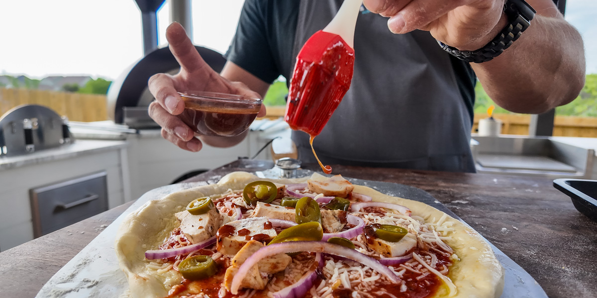 topping pizza dough with sauce chicken onion jalapeno and bbq sauce