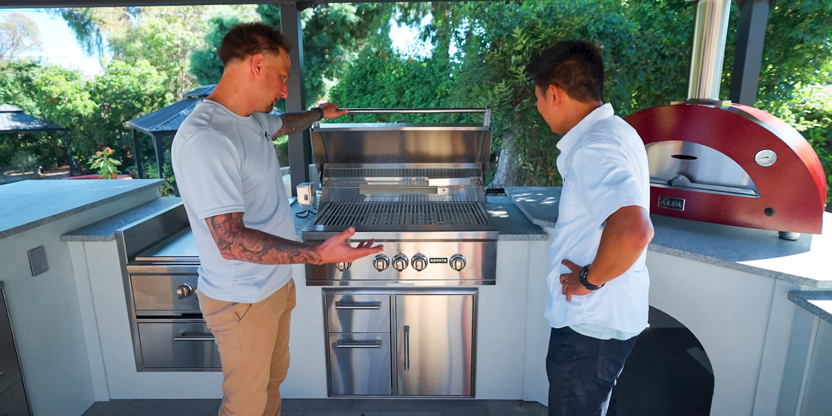 two guys looking at built in grill in outdoor kitchen