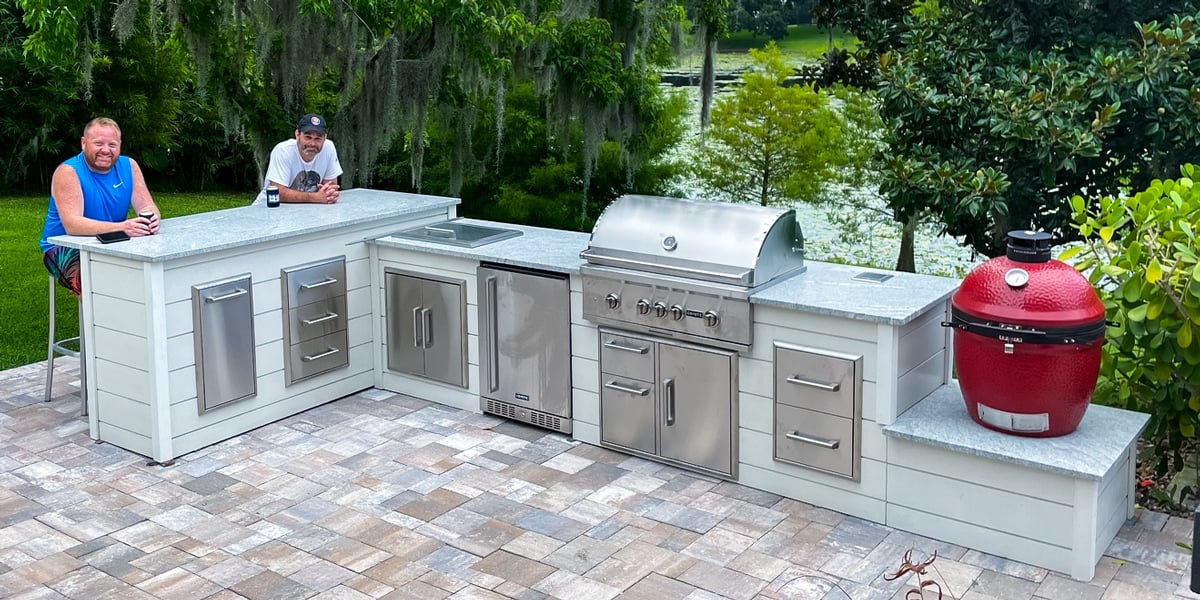 two guys relaxing at an l shaped outdoor kitchen