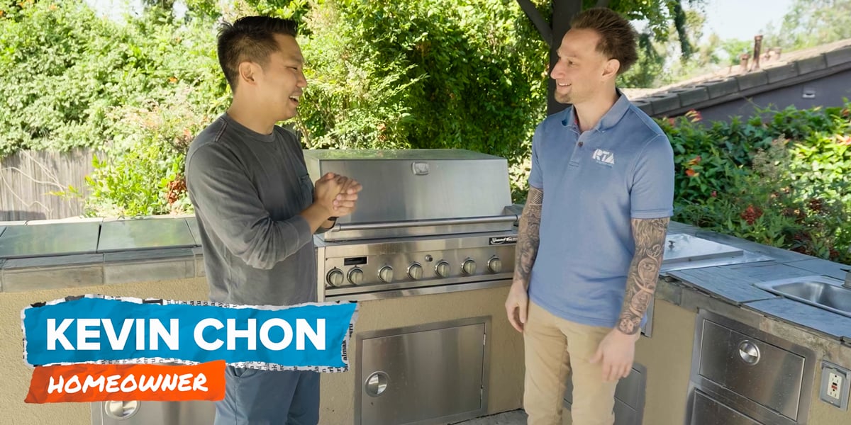 two men having a conversation in front of an outdoor kitchen