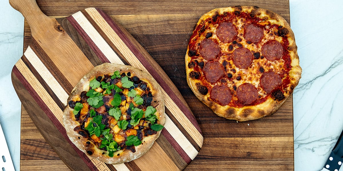 two whole pizzas on cutting boards