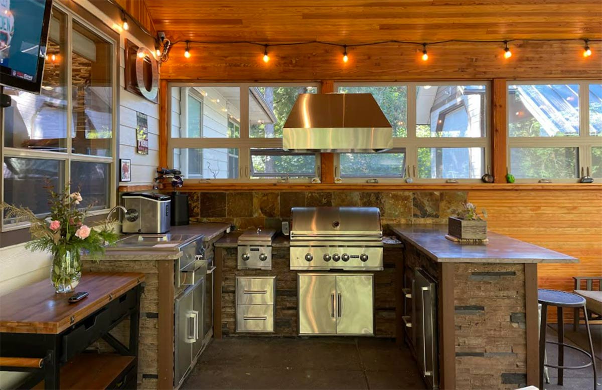 u shaped outdoor kitchen with vent hood and stone backsplash