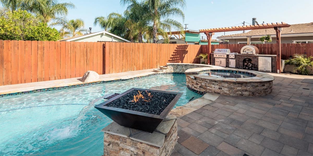 water feature with fire pit next to outdoor kitchen under pergola