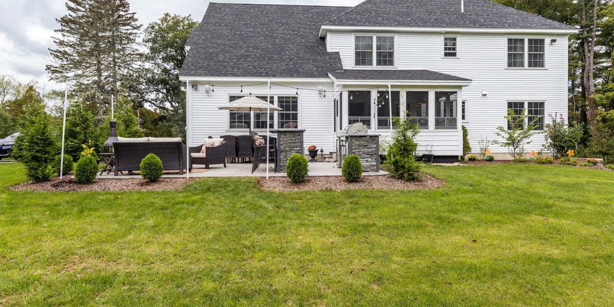 white house with large backyard seating area and outdoor kitchen