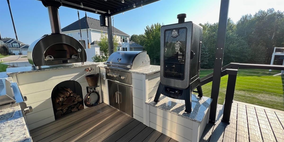white outdoor kitchen with electric smoker on pedestal