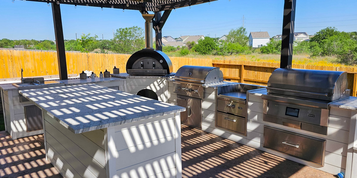 white outdoor kitchen with pizza oven gas grill and pellet grill
