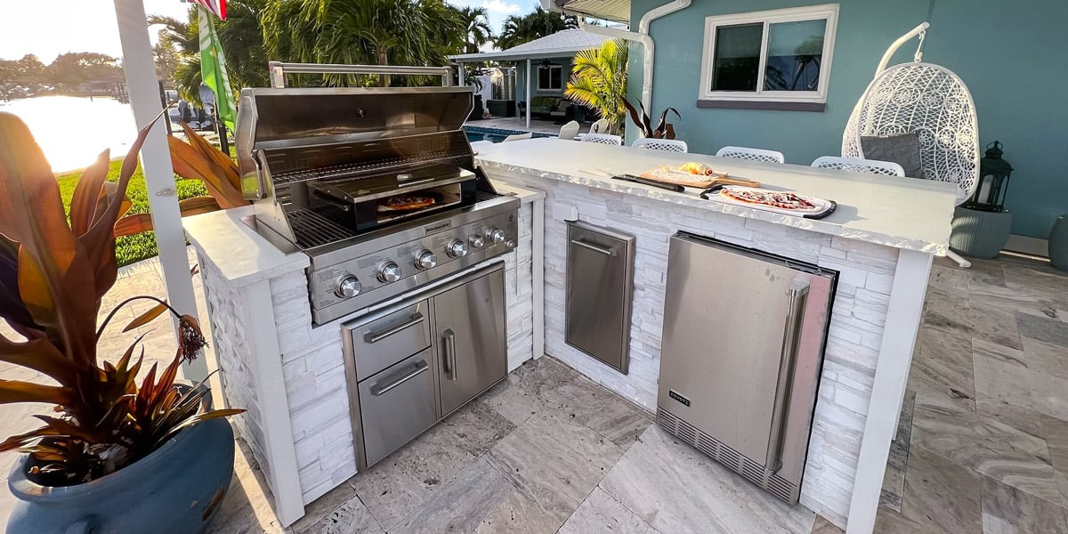 white stacked stone outdoor kitchen with gas grill